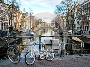 Bike on the bridge and reflection of Amsterdam famous duch traditional Flemish brick buildings on the canal